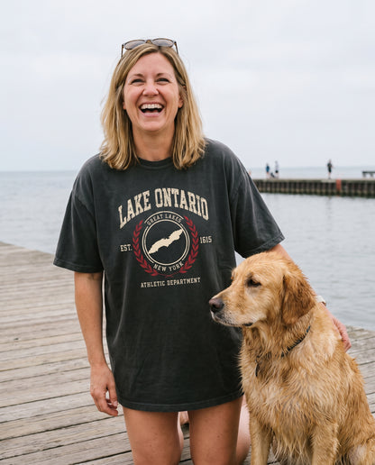 Lake Ontario Athletic Department tee in Black, on the boardwalk with a golden retriever