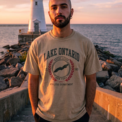 Lake Ontario Athletic Department tee in Faded Khaki, worn on a breakwall at sunset